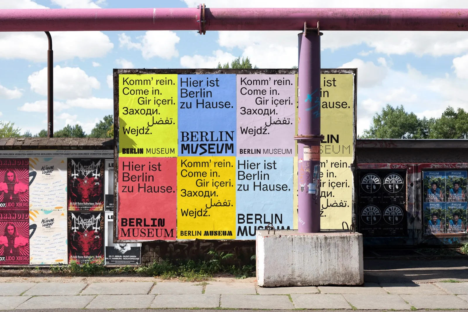 Carteles del nuevo sistema de identidad del Berlin Museum pegados sobre un muro de la ciudad, cada uno con una combinación tipográfica distinta del wordmark en amarillo, azul, rosa y rojo.