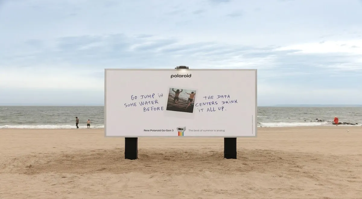Valla de Polaroid en una playa: sobre fondo blanco, una foto instantánea de dos personas saltando al agua y el mensaje manuscrito "Go jump in some water before the data centers drink it all up", con el logo de la campaña "New Polaroid Go Gen 3 — The best of summer is analog".